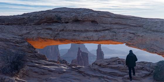 Rare Solitude at Mesa Arch Person in front of Mesa Arch 45 minutes after sunrise. By then most have left.