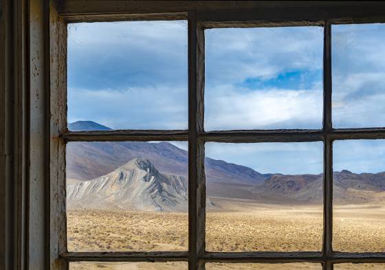 Striped Butte seen from a window in the Geologist's Cabin Geoloigists Cabin Window framing Striped Butte in Butte Valley, part of Death Valley, California