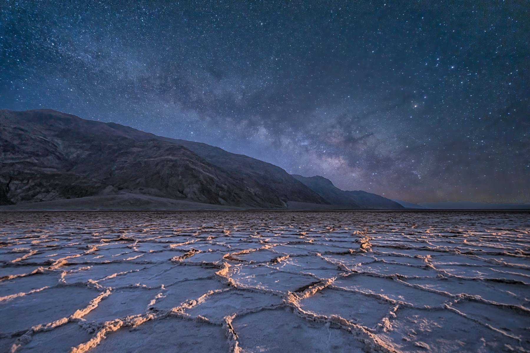 Badwater salt ridges lit by a light panel at night and the Milky Way in Death Valley National Park