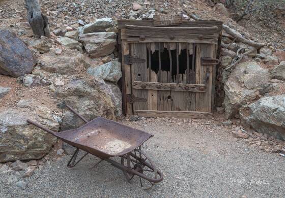 Mine Entrance Closed mine entrance and wheelbarrow seen at Vulture City ghost town, Arizona.